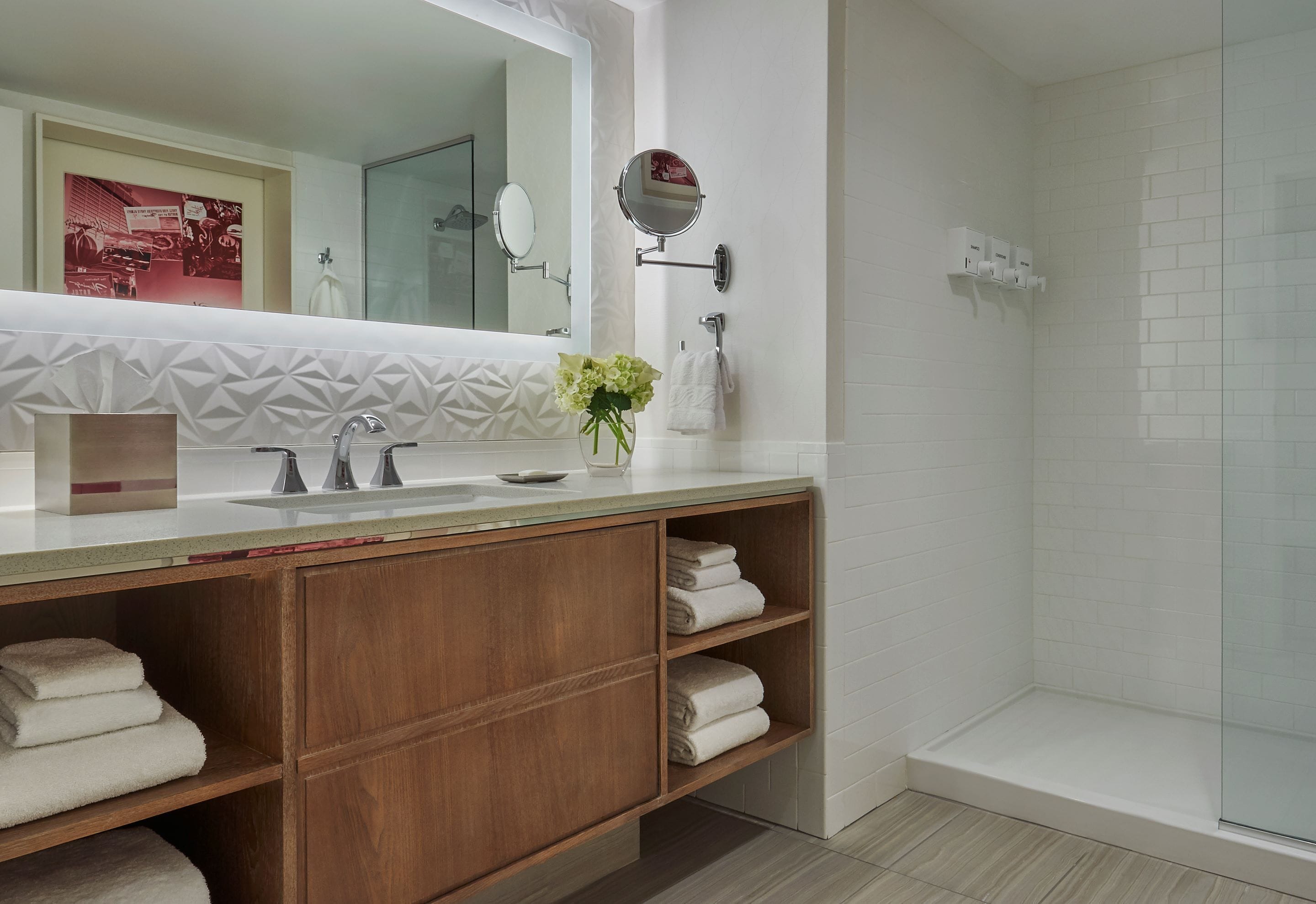 A modern bathroom with a vanity, a mirror, a shower, and a towel rack.