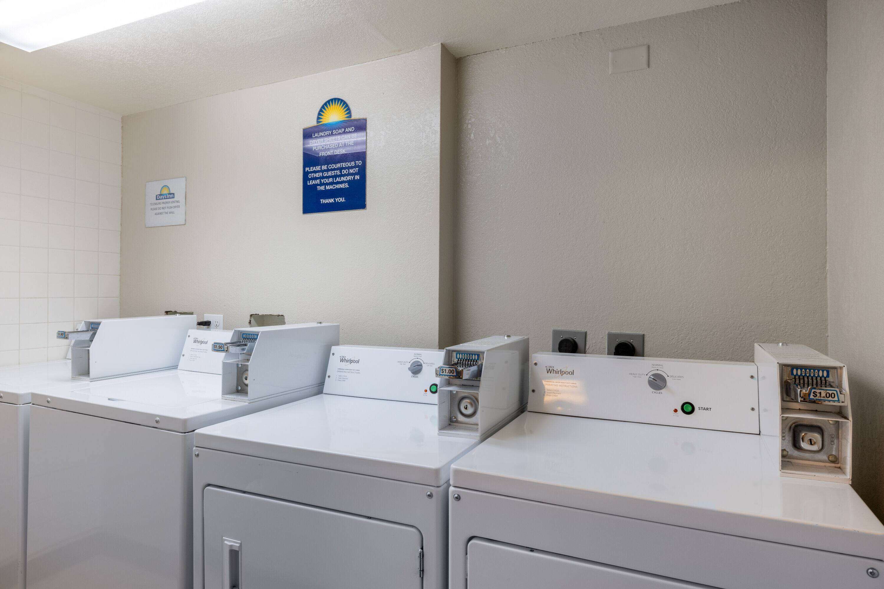 Ein Waschbereich mit drei Whirlpool Waschmaschinen und Trocknern, einem Schild für Bayhill Laundry Services und einer Information zur Nutzung der Geräte.