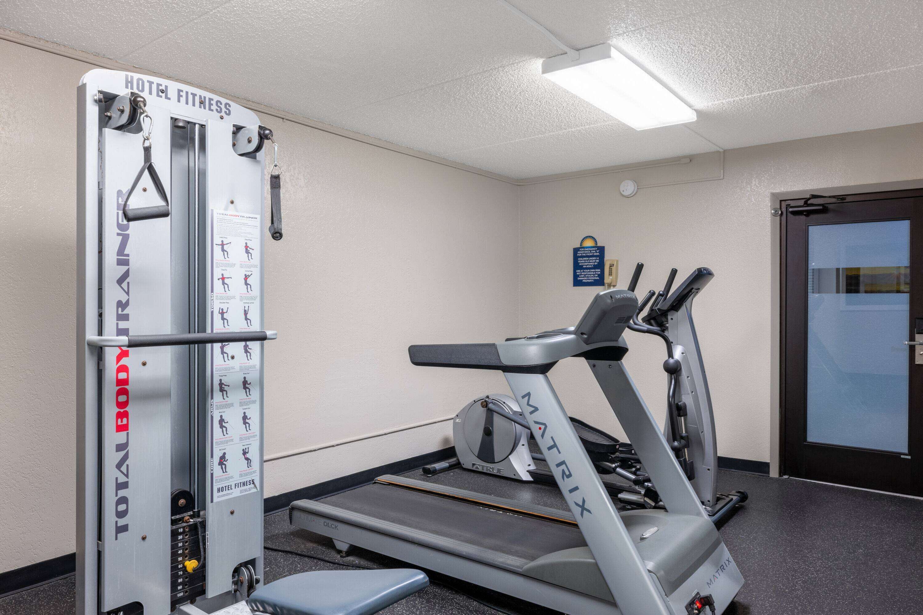 A hotel fitness center with a total body trainer, a treadmill, and a stationary bike.