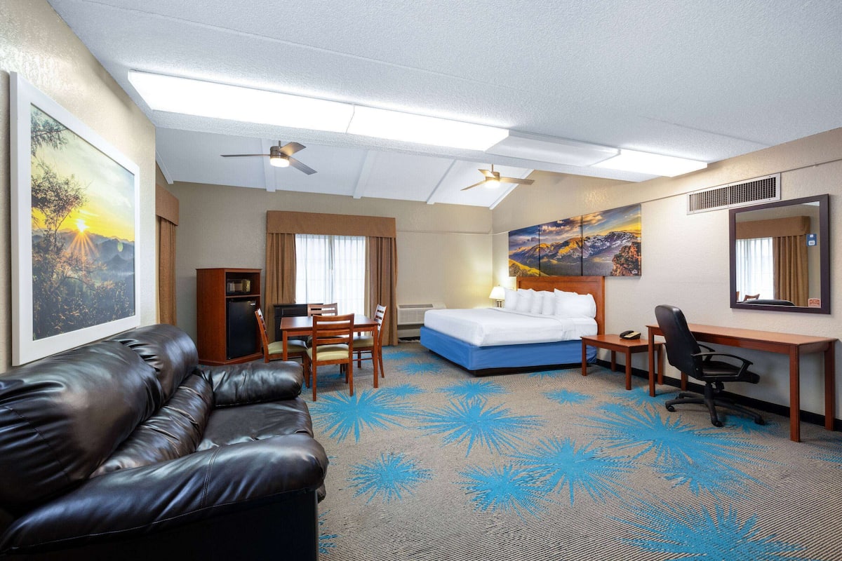 A hotel room with a bed, desk, chair, and a leather sofa.