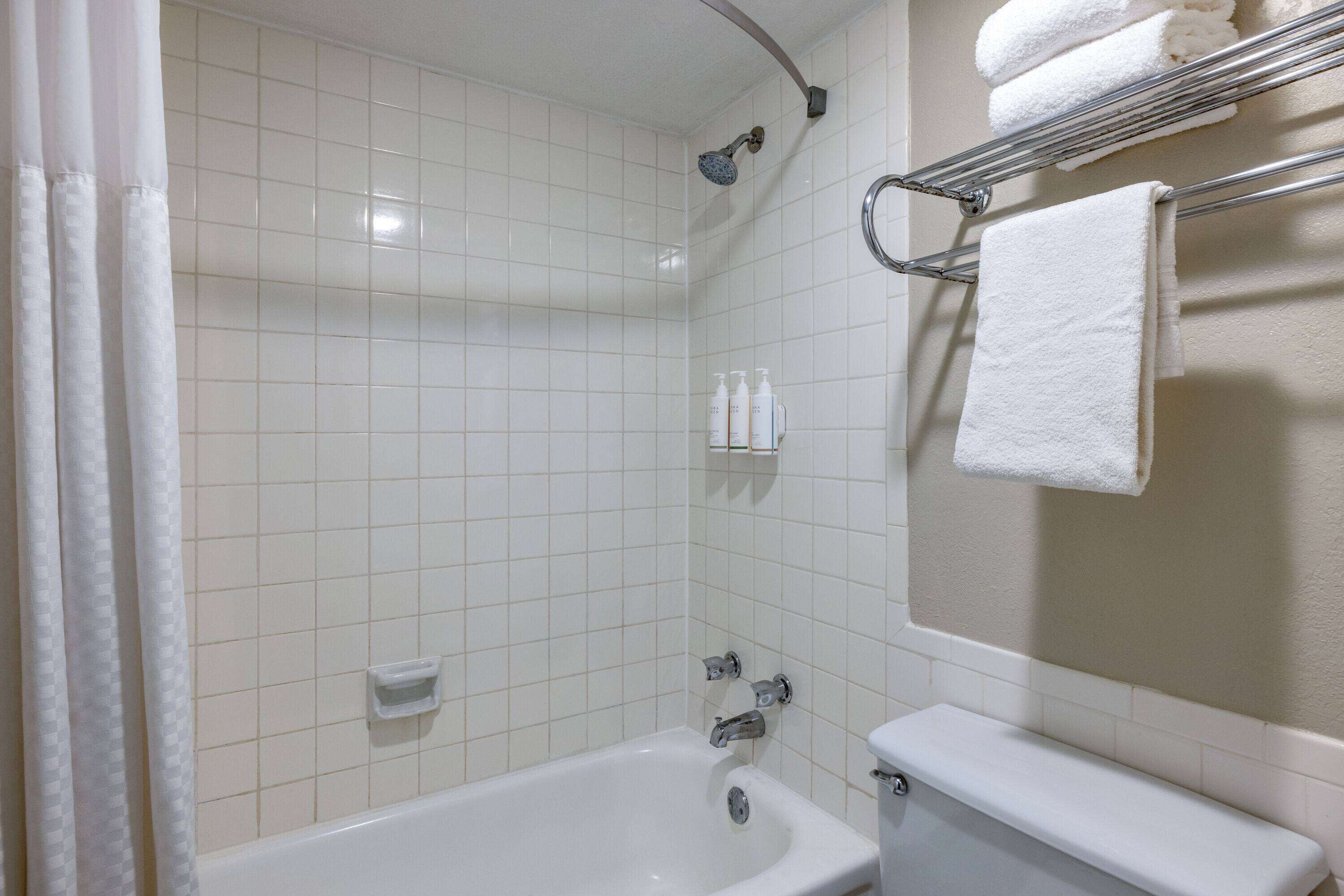 Kylpyhuoneessa on kylpyamme, wc, pyyhekoukku pyyhkeineen ja hylly, jossa on hygieniatuotteita.
