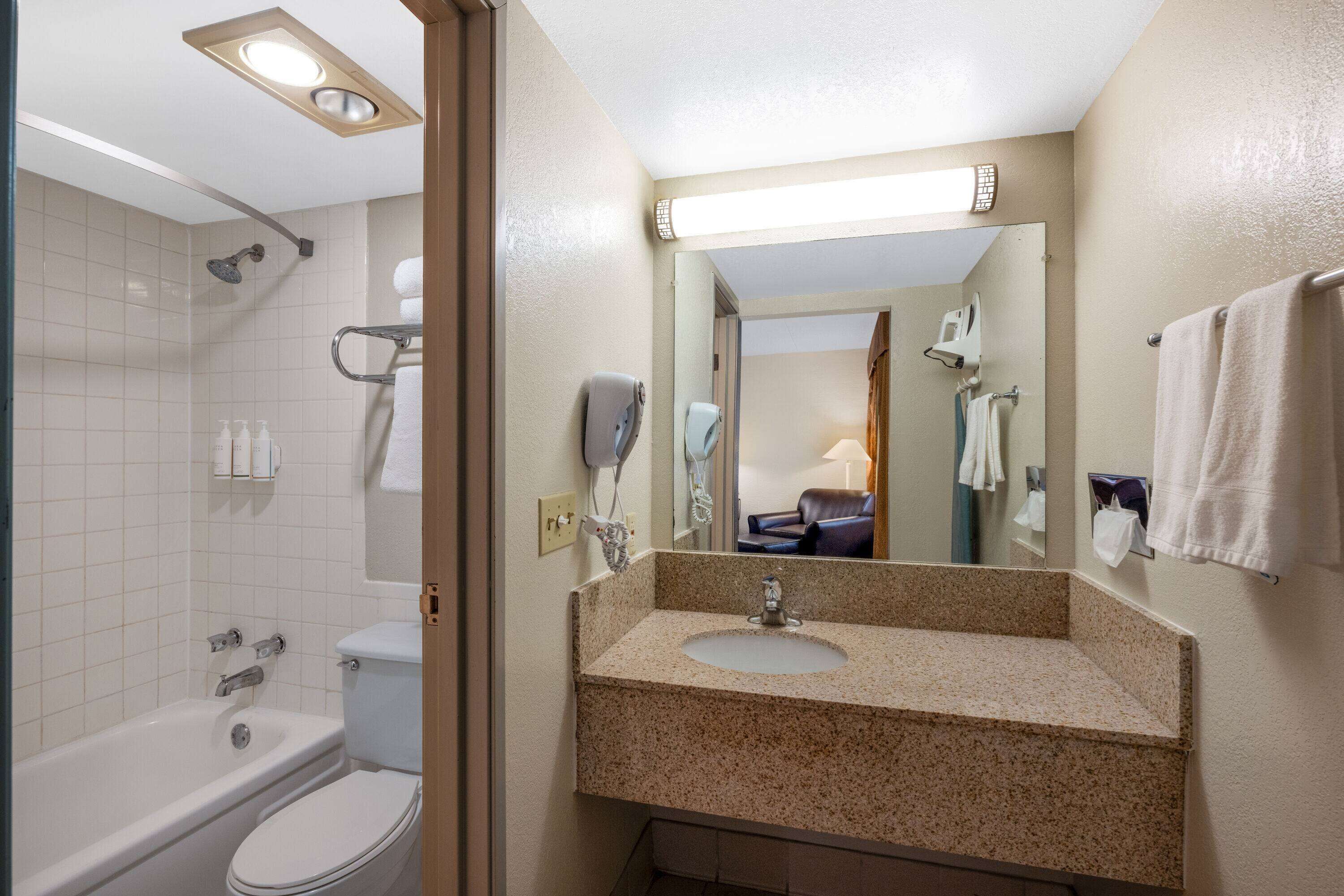 Un baño con bañera, inodoro, lavabo y espejo.