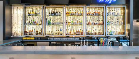 A bar area with a neon sign reading "wxyz" and shelves stocked with various bottles.