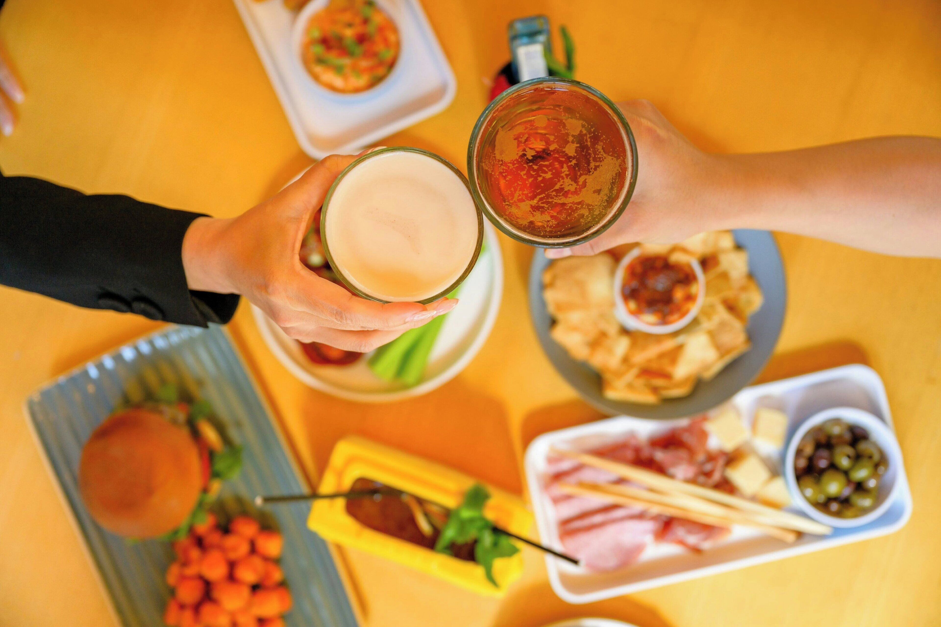 Uma mesa com diversos alimentos, incluindo um hambúrguer, queijo e azeitonas.