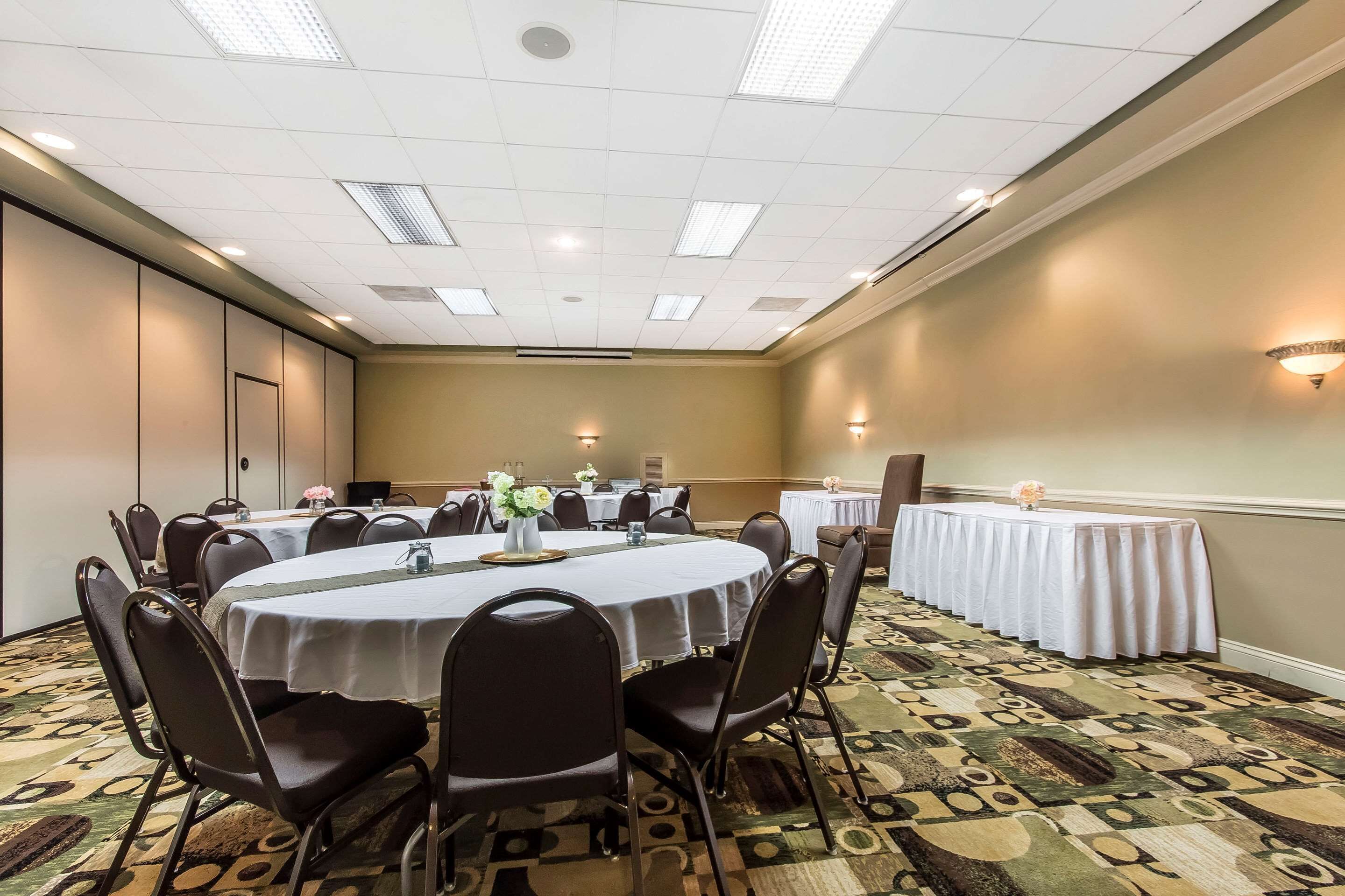 A conference room with round tables, chairs, and a patterned carpet.