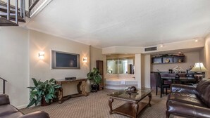 A living room with a sofa, coffee table, and a TV mounted on the wall. There is a staircase leading to an upper level, and a dining area with chairs and a table. - Clarion Inn Morgan City (Morgan City)
