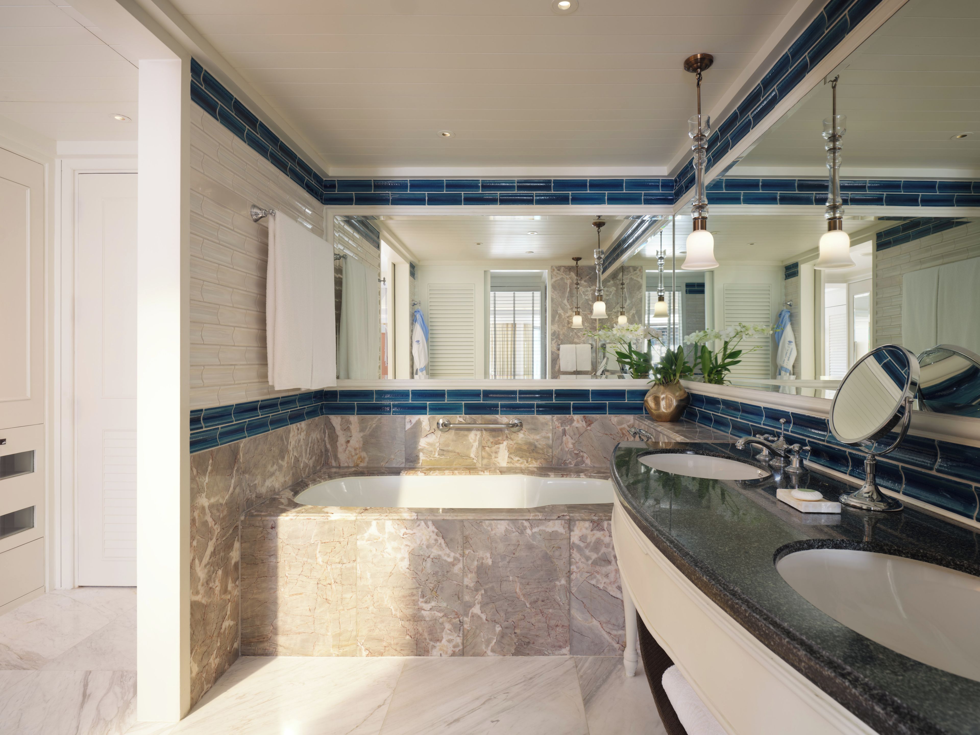 A modern bathroom with a dual sink vanity, a large bathtub, and a marble floor.