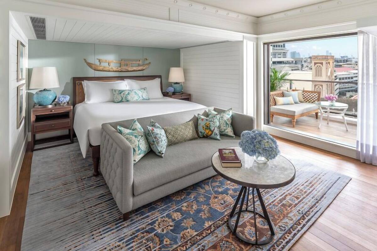 A bedroom with a bed, a sofa, a small table, and a balcony with a view of the city.