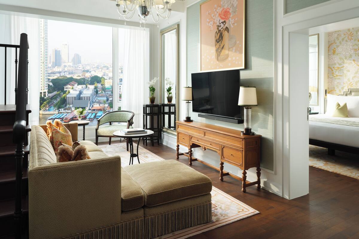 Un salón amplio con un televisor grande, asientos cómodos y vistas a la ciudad a través de grandes ventanales.