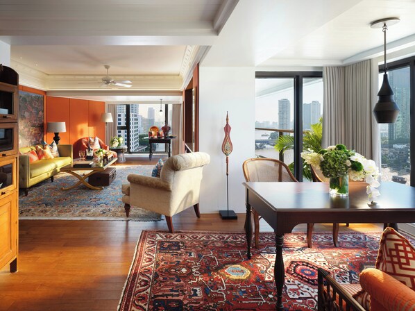 A spacious living area with a large window, a dining table, and a sofa. - Mandarin Oriental, Bangkok (Bangkok)