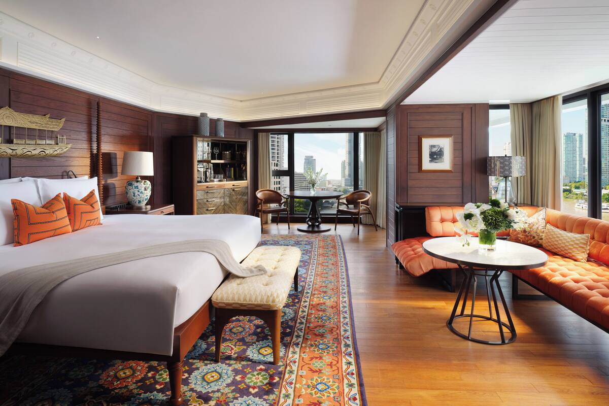 Habitación de hotel con una cama grande, un sofá, una mesa de comedor y vistas a la ciudad.