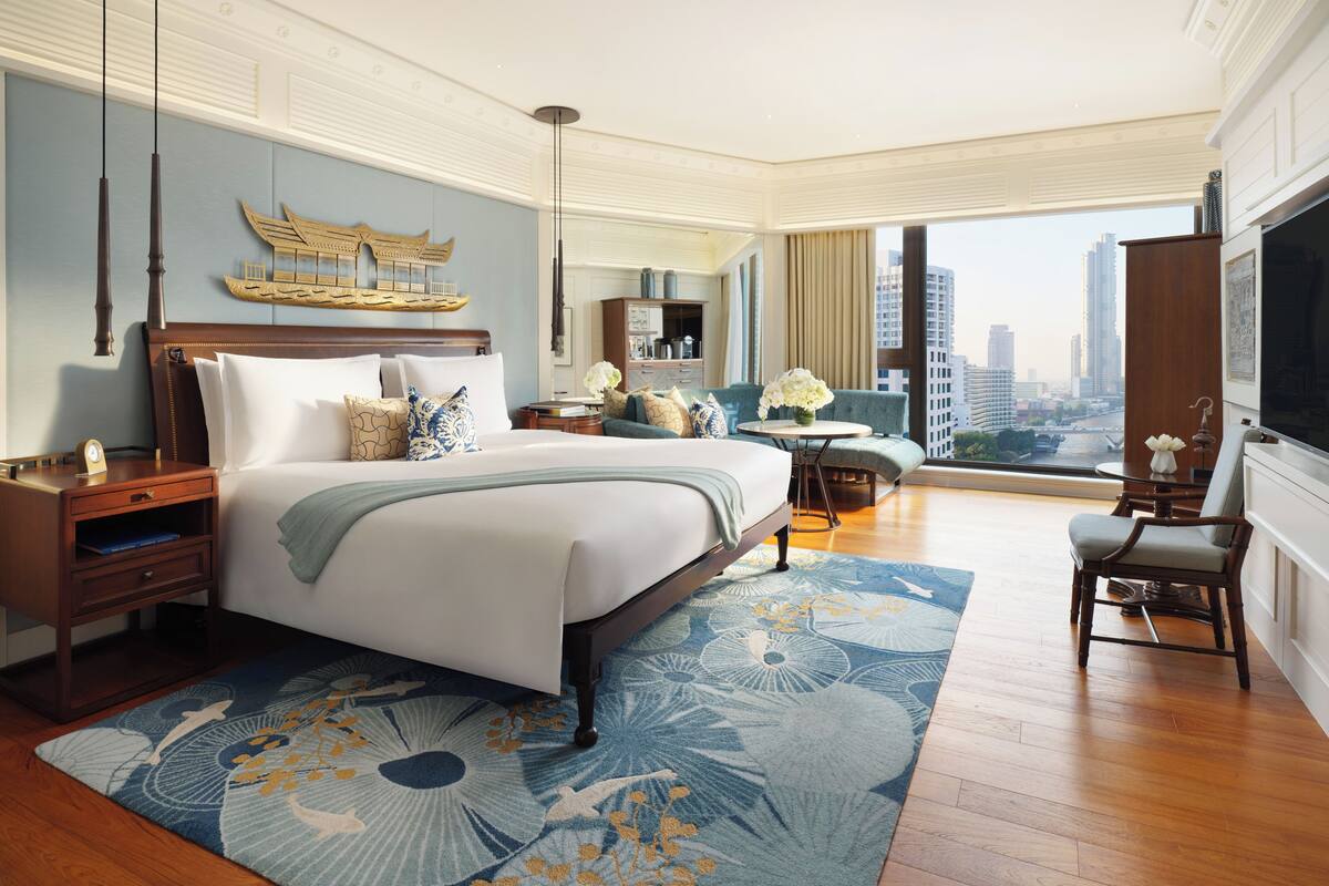 Una habitación de hotel espaciosa con una cama grande, vistas de la ciudad y un balcón con vista panorámica.