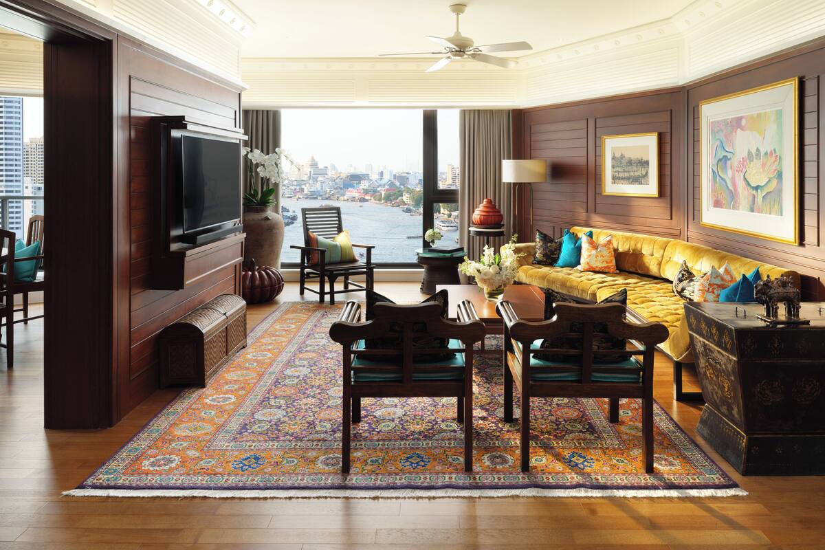 Un salón amplio con televisor grande, asientos cómodos, vista a la ciudad y un tapete decorativo.