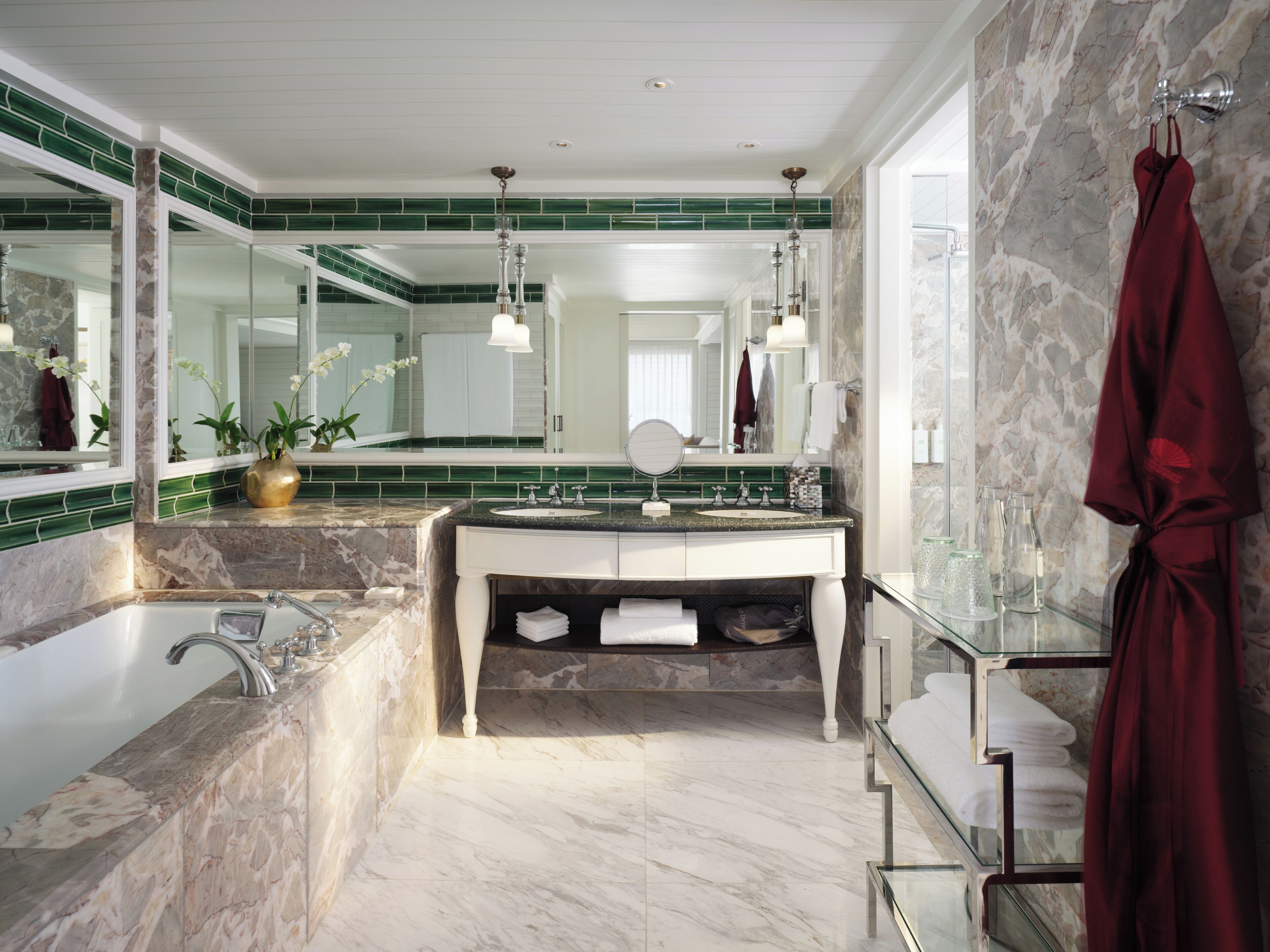 A modern bathroom with a marble sink, a large mirror, and a glass-enclosed shower.