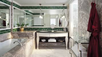 A modern bathroom with a marble sink, a large mirror, and a glass-enclosed shower.