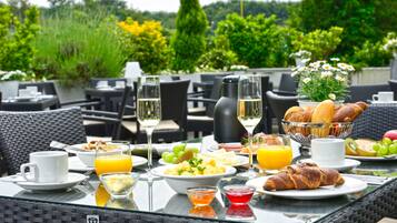 Una mesa de desayuno con diferentes alimentos, bebidas y un centro de mesa floral.