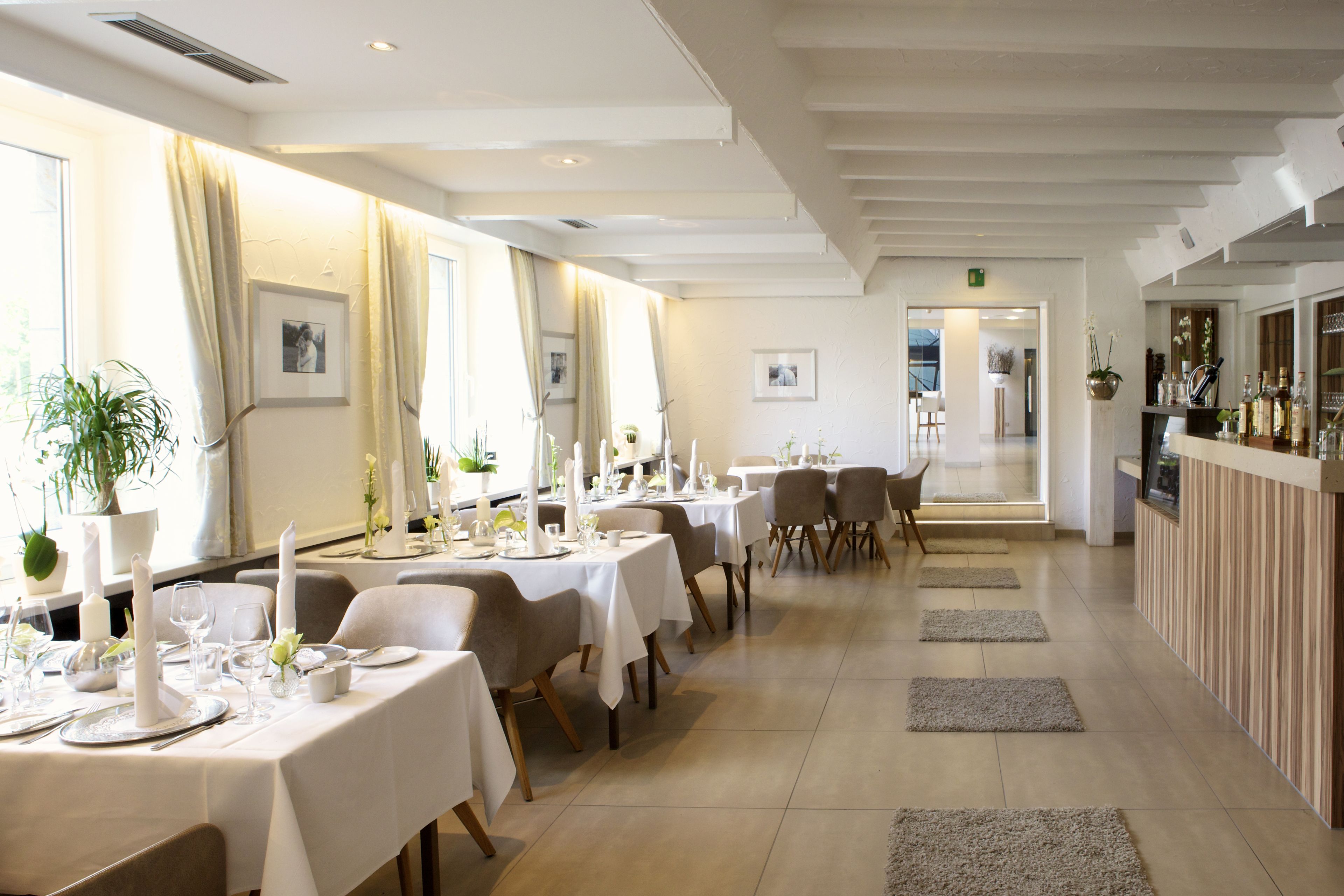 Un restaurante con varias mesas dispuestas para comer, una zona de bar y vistas al exterior.