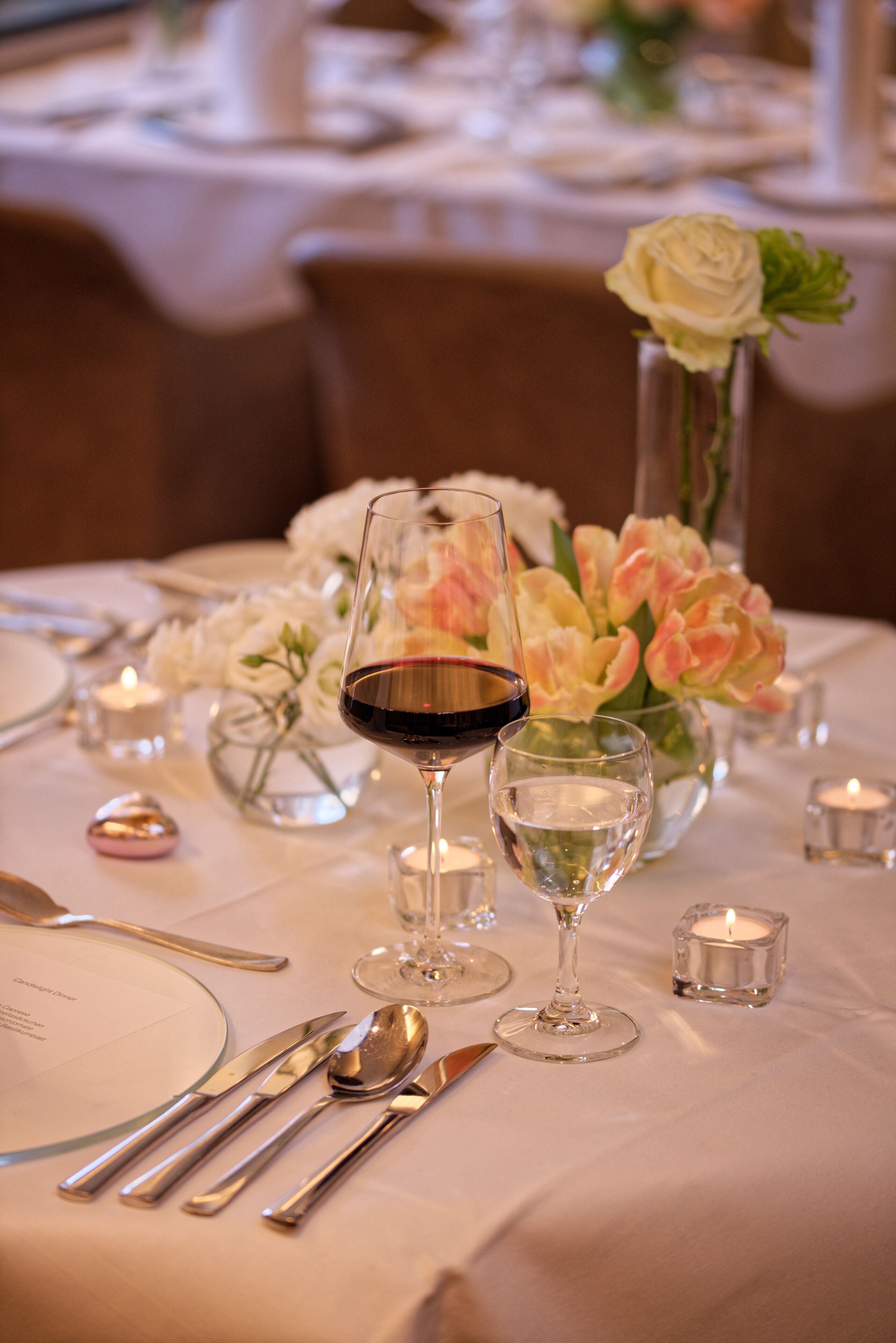A table set for dining with wine glasses, cutlery, and candles.