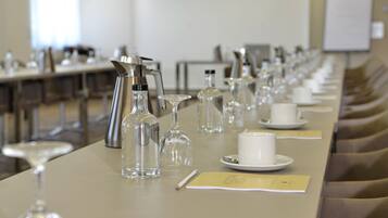 A conference room with a long table set for a meeting, equipped with microphones, water bottles, and nameplates.