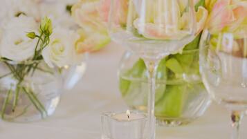 A table set with clear glassware, white flowers, and a lit candle.