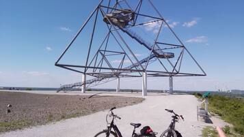 A bicycle path with two bicycles parked, leading to a large metal structure.