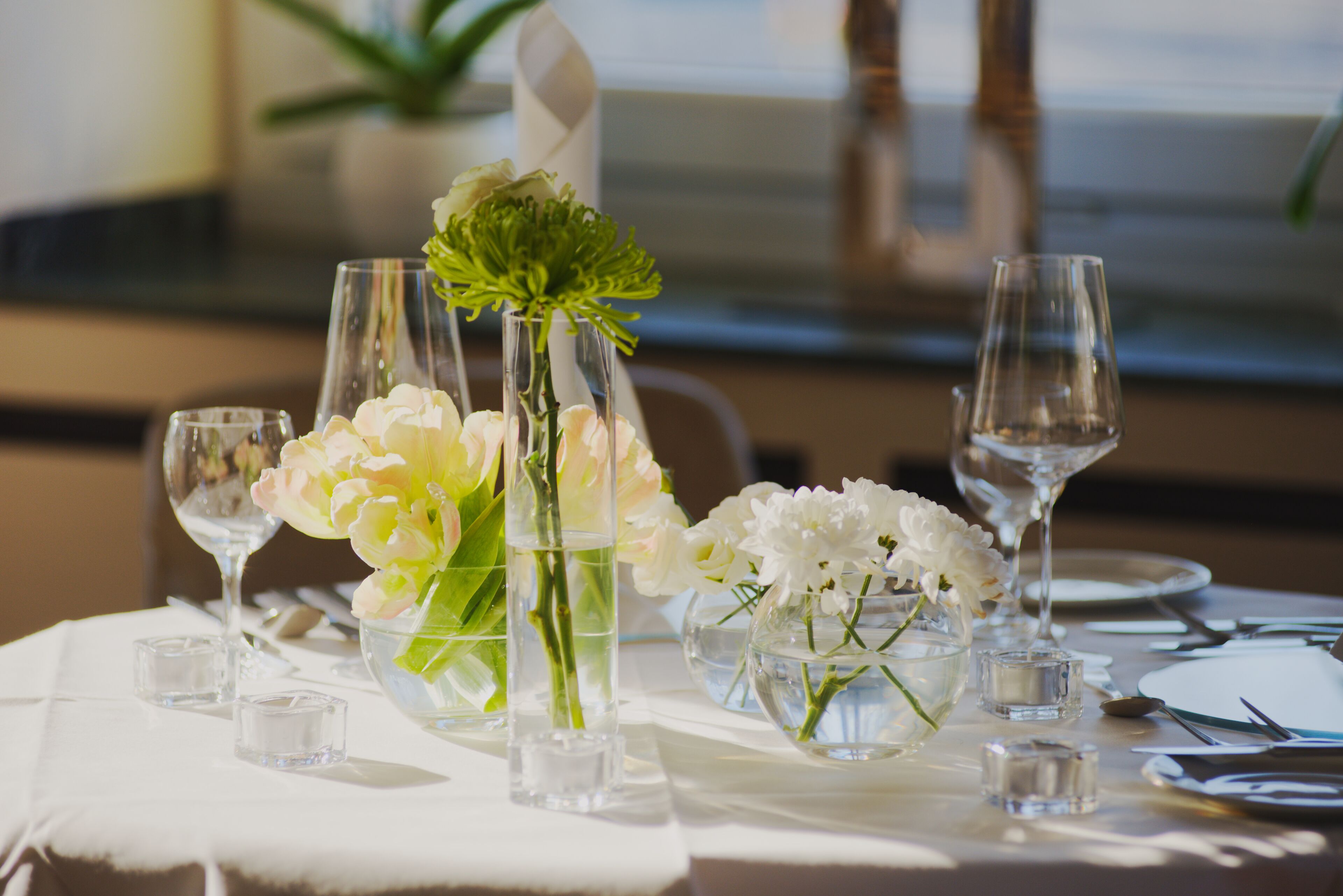 A table set for a formal dining occasion with clear glassware, white flowers, and a clean tablecloth.