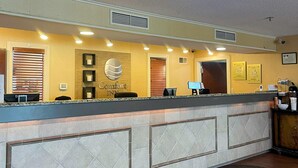 Un espace d’accueil avec un comptoir, une enseigne indiquant « Comfort Inn » et une horloge fixée au mur.