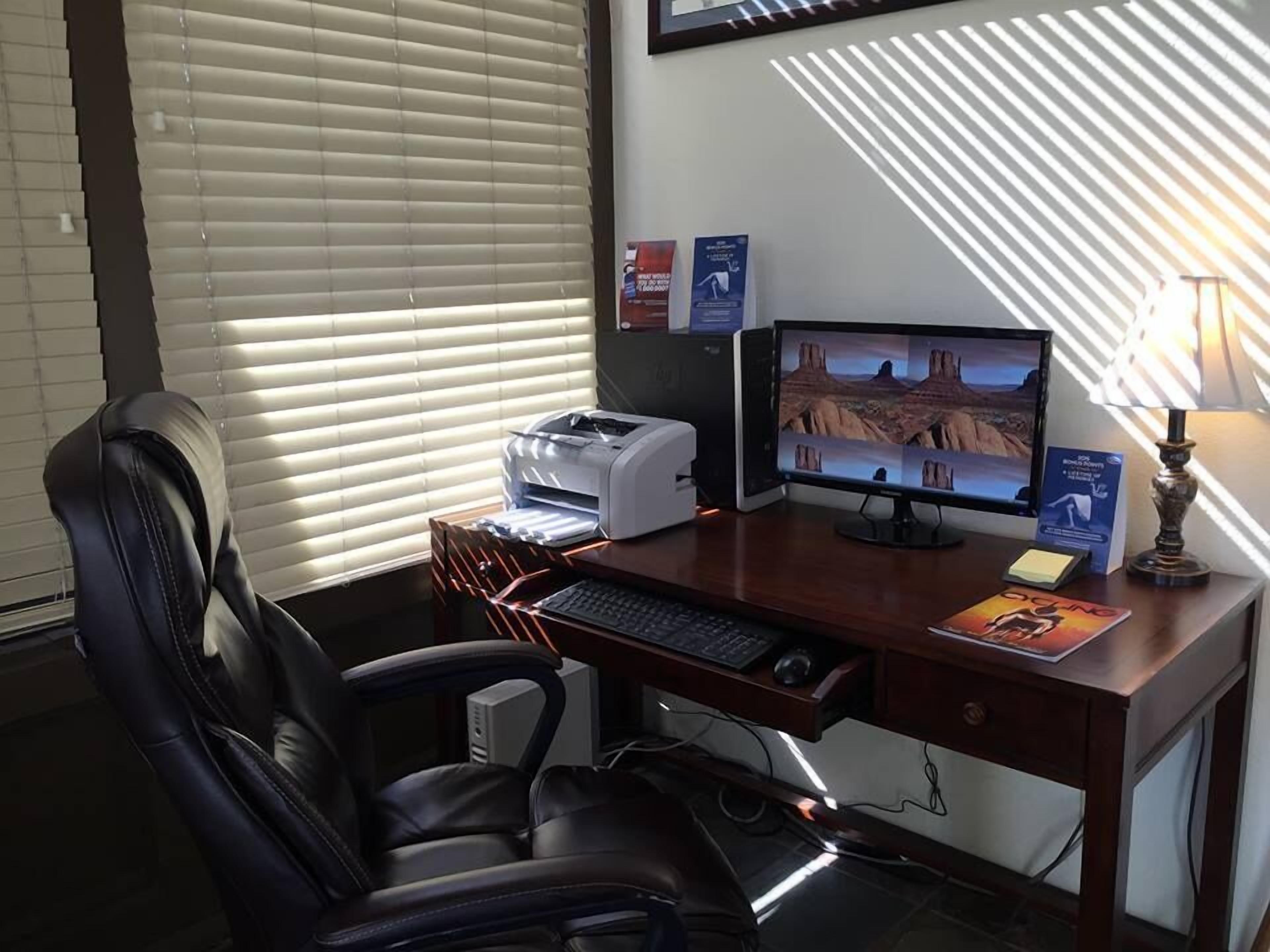 Ein Home-Office-Arbeitsplatz mit Schreibtisch, Computer, Drucker und Stuhl.