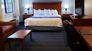 Ett hotellrum med en stor säng, två sänglampor, en tv, ett skrivbord och en stol.