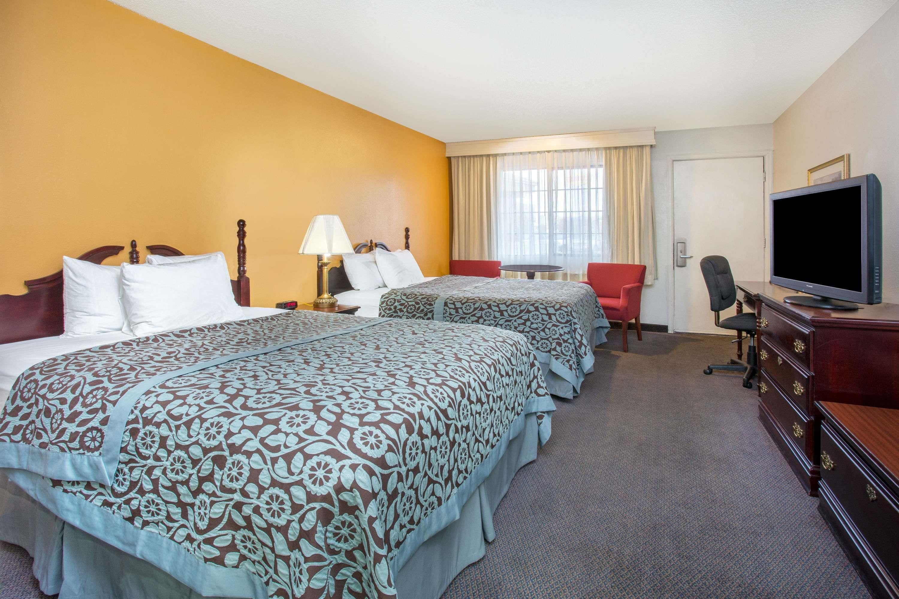 Una habitación de hotel con dos camas, televisión, escritorio y una silla.