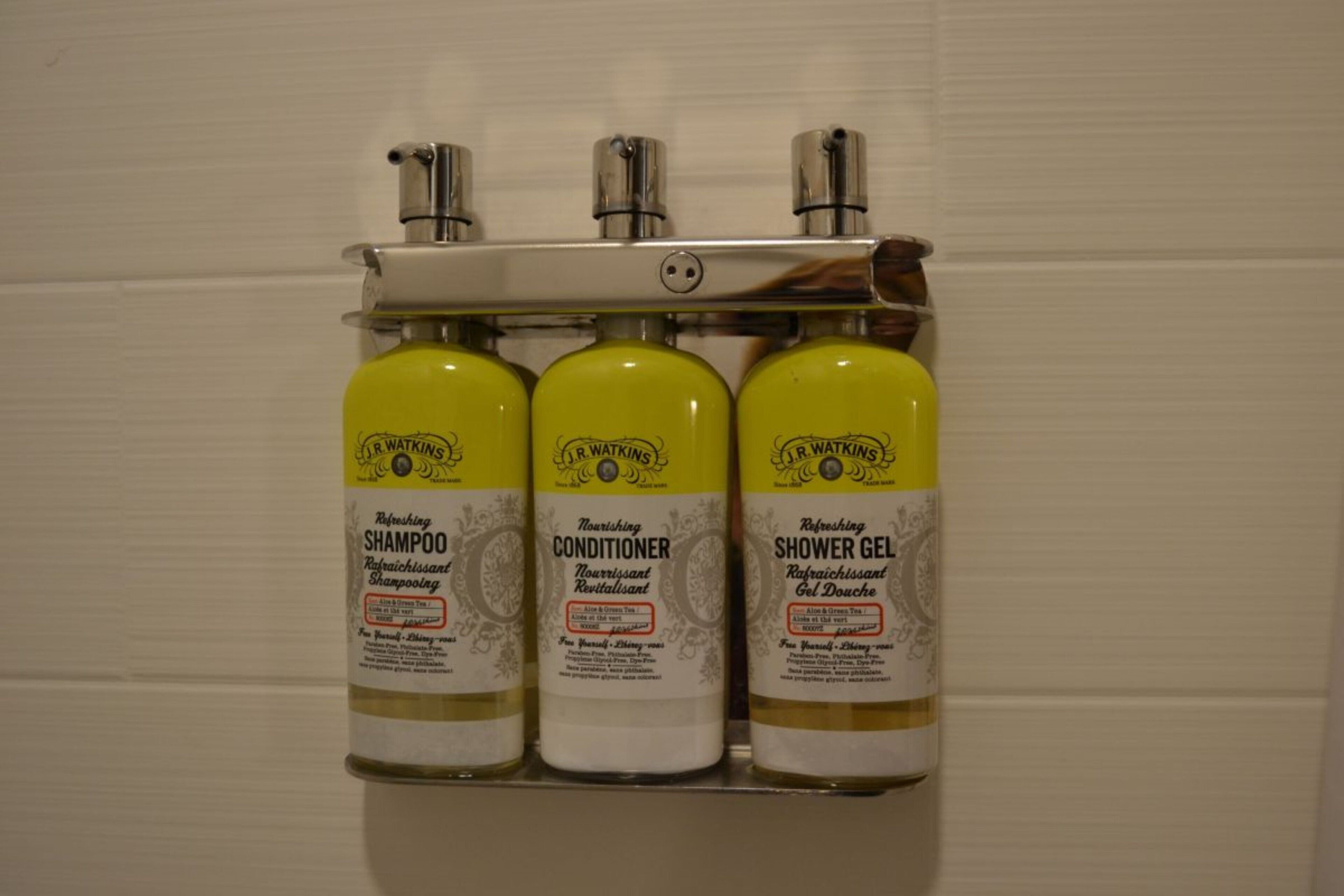 Three bottles of J.R. Watkins personal care products mounted on a wall.