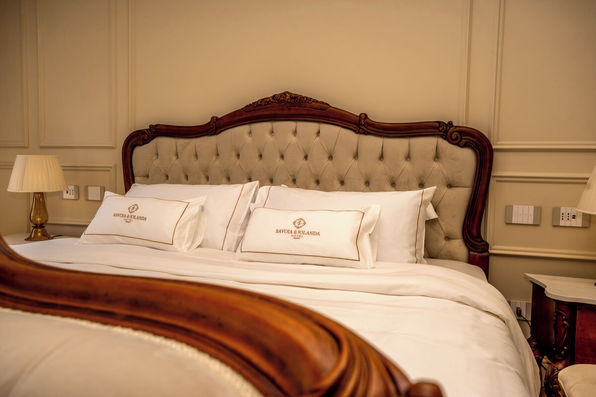 A hotel room with a tufted headboard, a bed with white linens, and two bedside lamps.