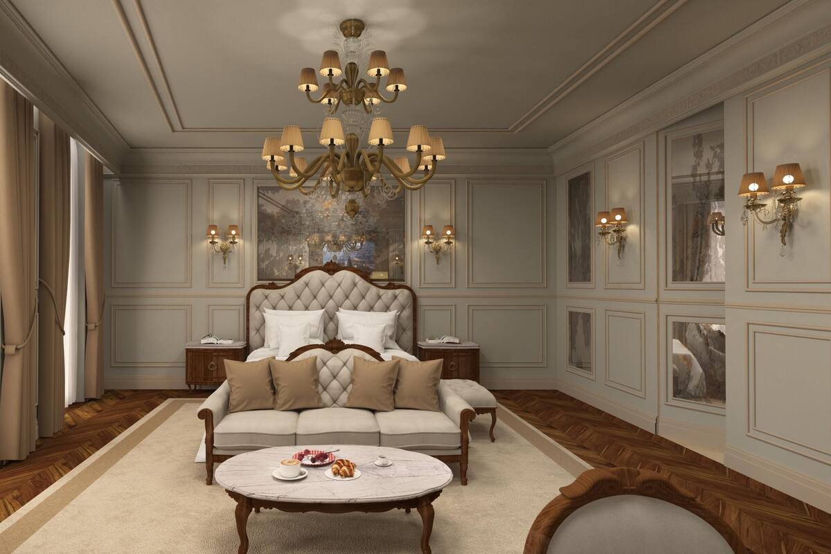 A luxurious bedroom with a large bed, a sofa, a coffee table, and a chandelier.