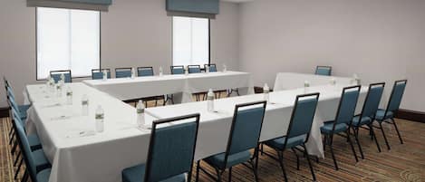 Ein Konferenzraum mit langen Tischen, Stühlen und großen Fenstern.