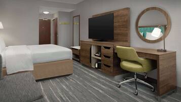 Quarto de hotel com cama, escrivaninha com televisão de tela plana, cadeira, espelho e piso coberto de carpete.