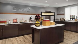 A modern kitchen with a central island, dark cabinets, and a breakfast bar. - Hampton Inn Haverhill (Haverhill)