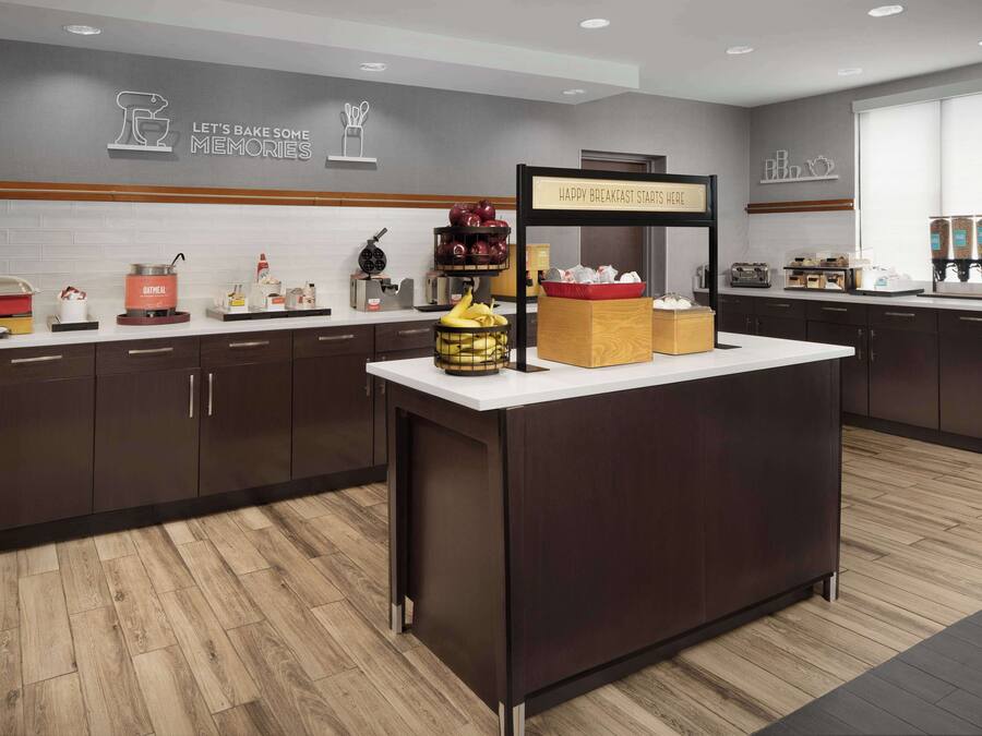 A modern kitchen with a central island, dark cabinets, and a breakfast bar.