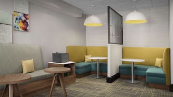 A modern lounge area with a sofa, two small round tables, and a large window.