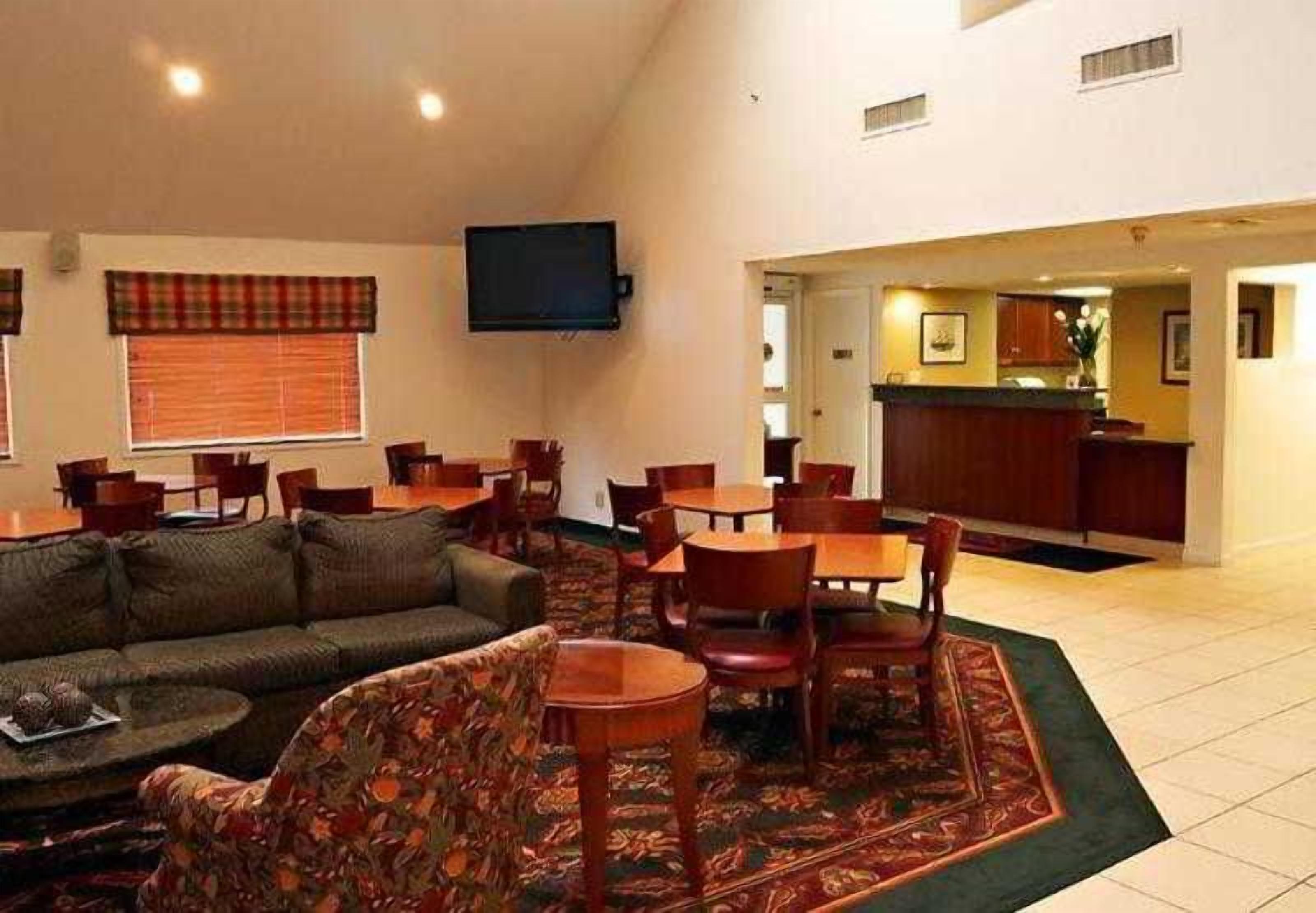A hotel room with a living area, dining table, and kitchen.