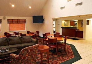 A hotel room with a living area, dining table, and kitchen.