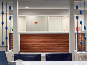 A modern reception area with a wooden panel wall, a red bird decoration, and blue hanging elements. - Sonesta ES Suites Providence - Airport (Warwick)