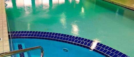A swimming pool with a blue tiled edge and a metal ladder.
