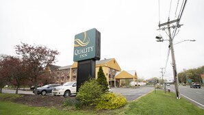 Un hotel Quality Inn con un cartello ben visibile, un parcheggio e una strada con delle auto.