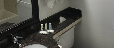A bathroom with a large mirror, a sink, a towel rack, and a toilet.