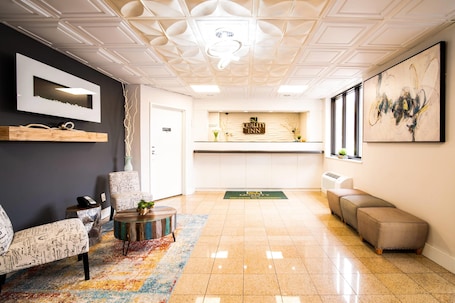 A hotel lobby with a reception desk, a wall-mounted TV, a sofa, a coffee table, and a patterned rug.. Quality Inn Cromwell - Middletown