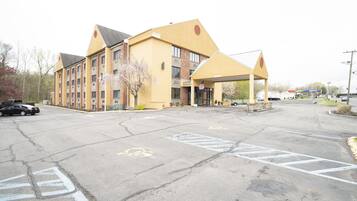 A multi-story hotel with a yellow facade and a covered entrance.