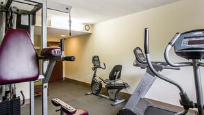 Una palestra con diverse attrezzature per l'allenamento, tra cui un tapis roulant, una ellittica e macchinari per pesi.