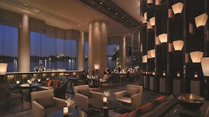 A spacious lounge area with high ceilings, large windows, and modern lighting fixtures.