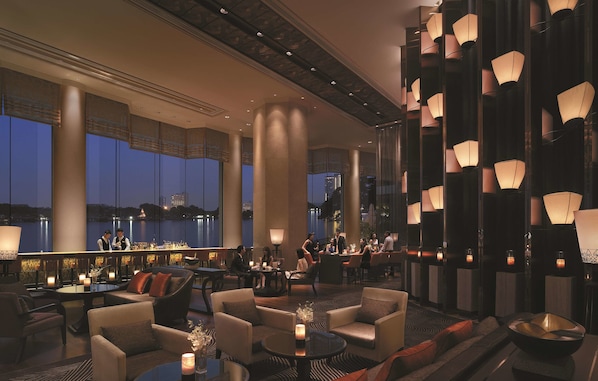 Un amplio salón con techos altos, ventanas grandes y luminarias modernas.