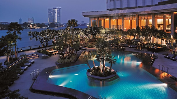 A pool area with lounge chairs and a view of the city skyline.